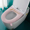 A white toilet seat with a pink plush waterproof cover and an open lid is shown on a teal surface.