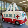 A white quilted travel duffle bag with red accents and a cross design is displayed on a gray surface.