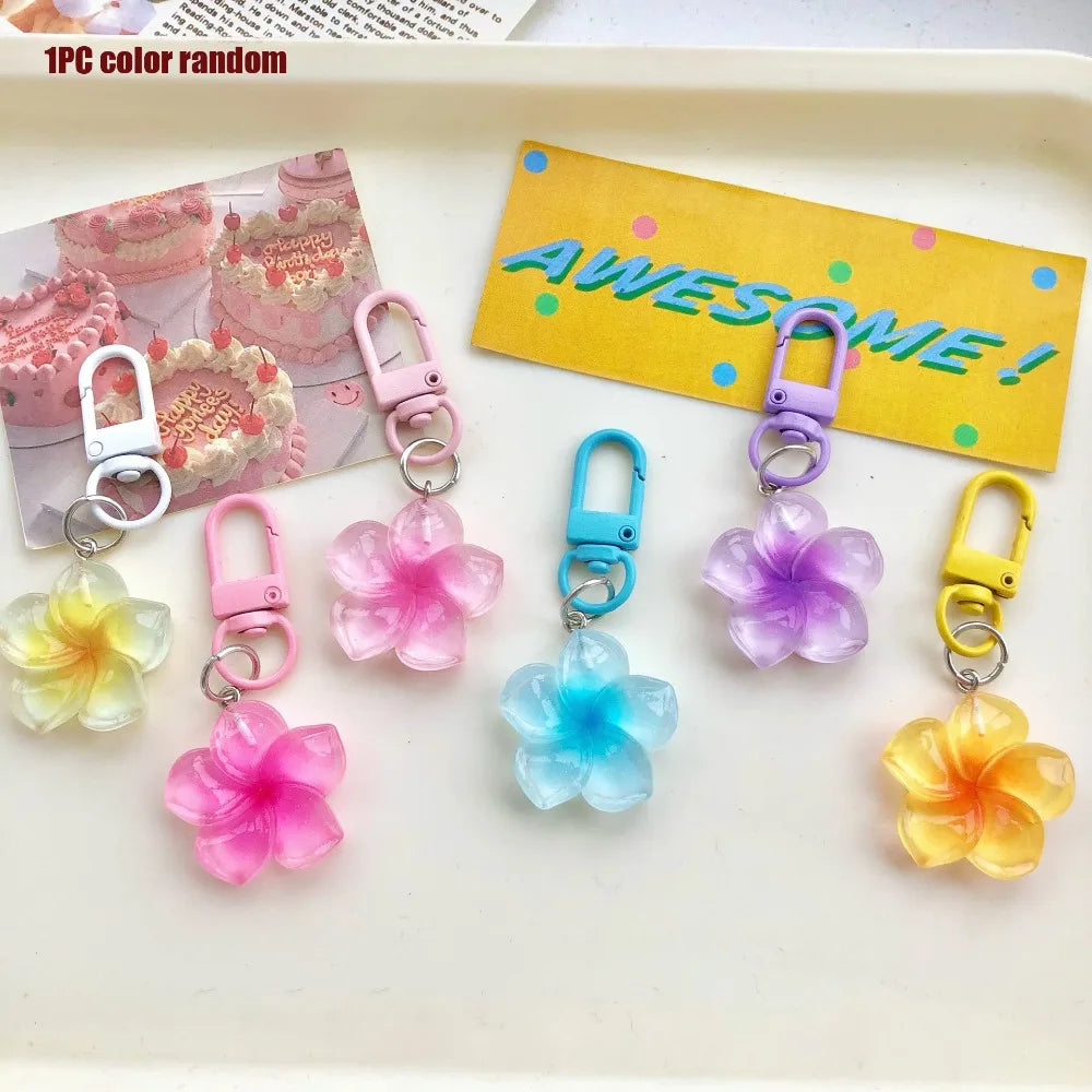 A collection of 12 colorful resin flower keychains in various shades of pink, purple, blue, and yellow displayed on a white t