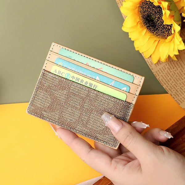 A hand holds a brown textured card holder with several cards inside, next to a yellow sunflower.
