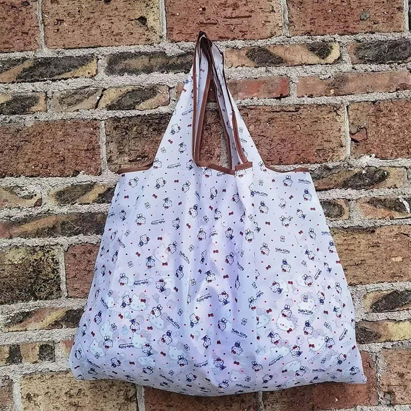 A white reusable shopping bag with a brown strap is displayed against a brick wall.