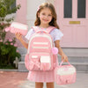 A young girl is smiling while holding a pink cartoon school bag set consisting of a backpack and a matching pouch.