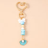 Gold and pearl starfish keychain featuring striped beads and a white bow.