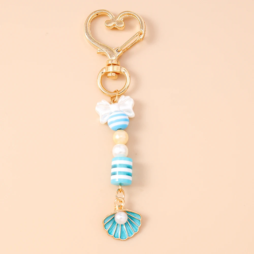 Gold and pearl starfish keychain featuring striped beads and a white bow.