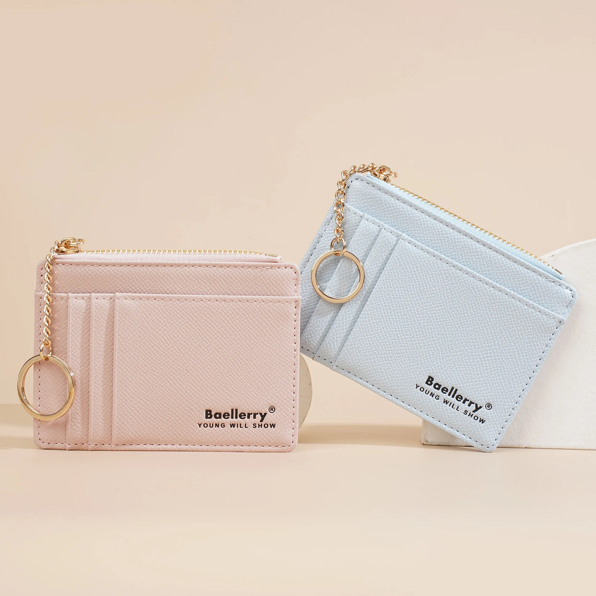 A light pink wallet and a light blue wallet are displayed next to each other on a beige surface.