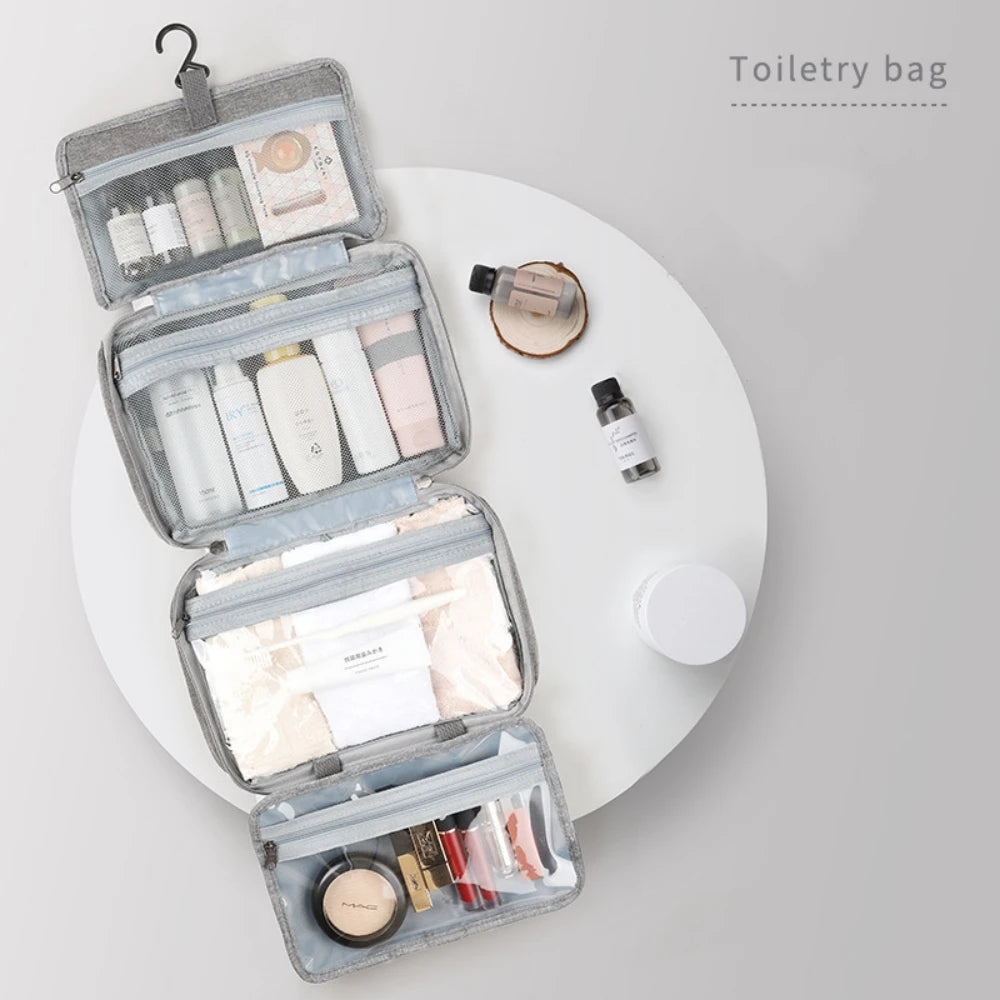 A gray toiletry bag with a hanging hook is open, showing various skincare and beauty products inside on a white surface.