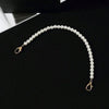 A strand of white pearls draped in a graceful arc against a black background.