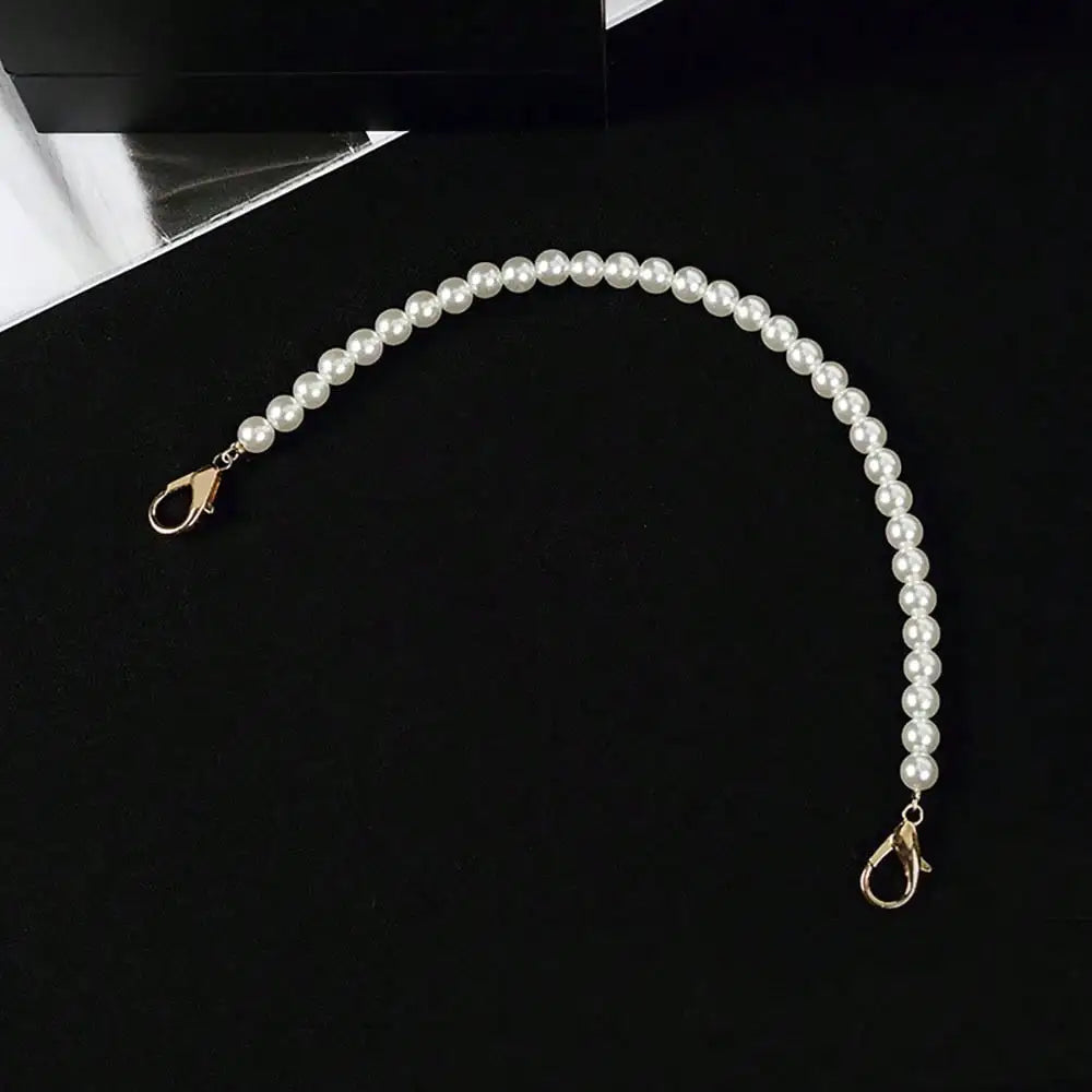 A strand of white pearls draped in a graceful arc against a black background.