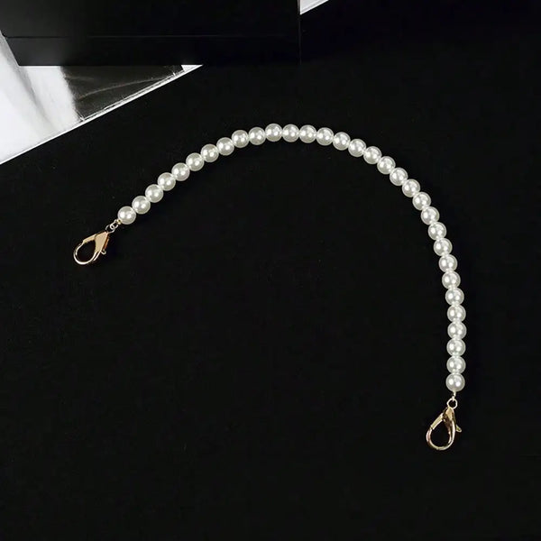 A strand of white pearls draped in a graceful arc against a black background.