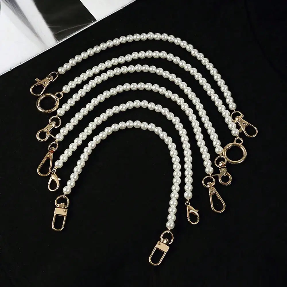 Elegant pearl strap for handbags featuring multiple strands of white pearls and gold-toned clasps.