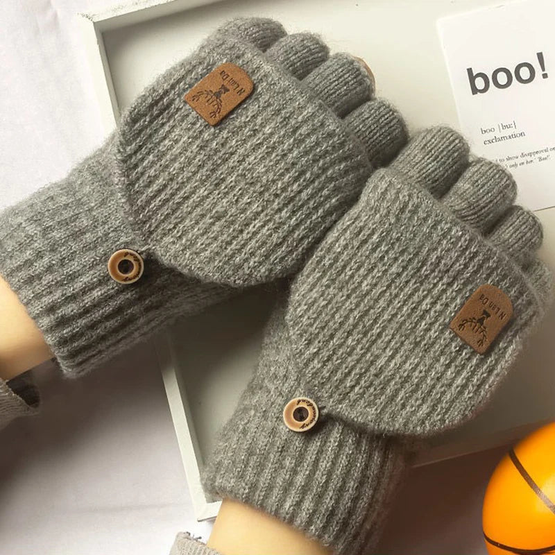 Nahaufnahme grauer gestrickter Fingerhandschuhe mit Holzknöpfen auf weißem Untergrund.