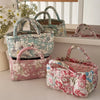 A collection of quilted fabric storage baskets in various floral patterns and pink tones displayed on a white shelf.