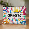 Bolsa con cremallera llena de varios cargadores y cables electrónicos sobre una superficie de madera.