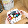 A white storage basket filled with various colored fabric scraps and yarn is shown on a wooden shelf.