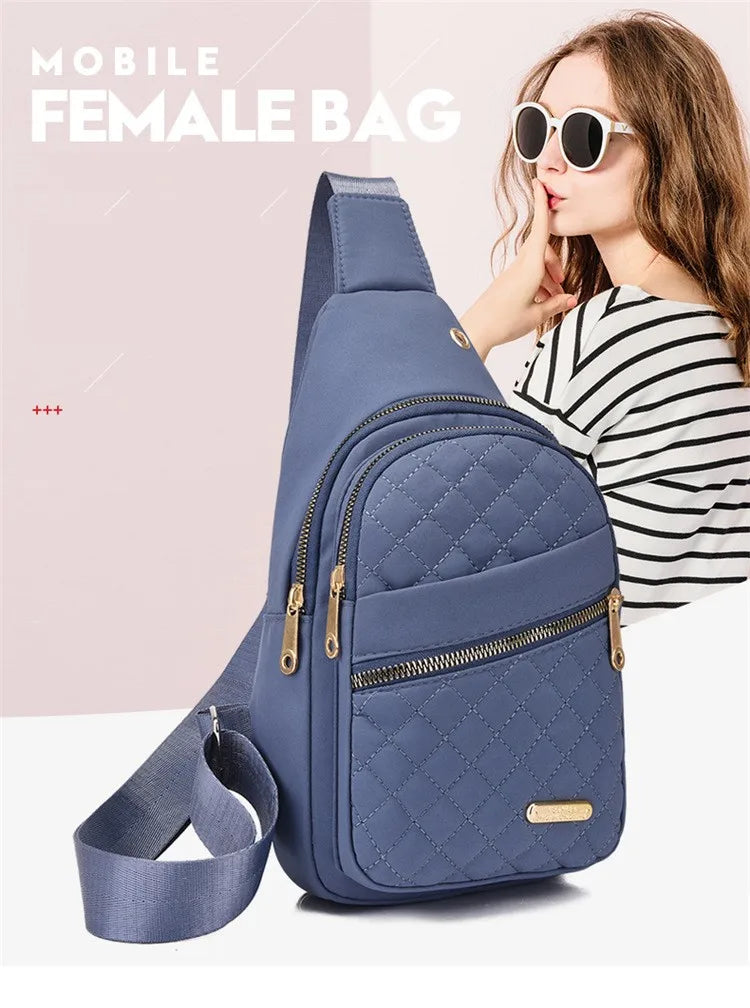Eine Frau hält eine blaue gesteppte Damenhandtasche mit Trageriemen, trägt Sonnenbrille und gestreiftes Hemd.