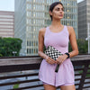 A woman wearing a light pink sleeveless dress holds a black checkered wallet with a clear ID window.