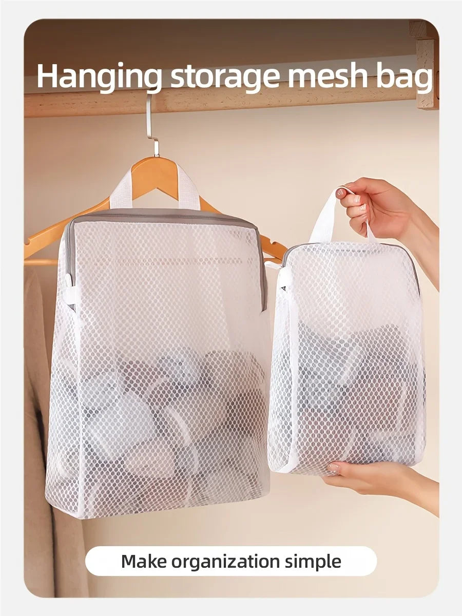 A white hanging storage mesh bag is displayed on a wooden hanger against a light wall, demonstrating simple organization.