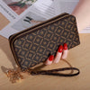 Cartera con cremallera de cuero sintético marrón y textura sobre una superficie de madera.