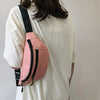 A pink nylon waist bag with black straps is worn on a white t-shirt.
