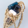 A handmade dumpling bag made of silver and gold beads, holding a smartphone and a clear container.