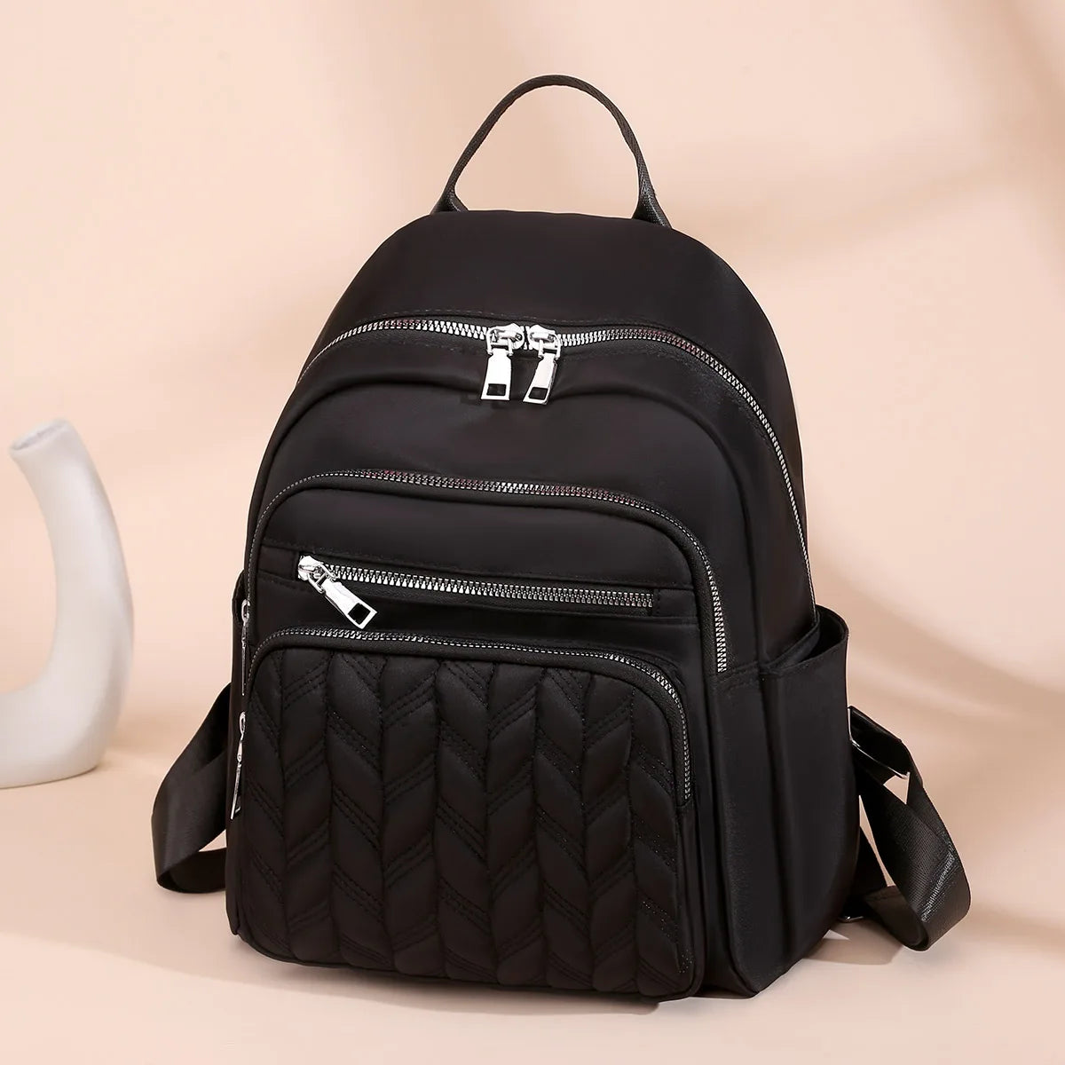 Black waterproof women's travel backpack with zippered compartments and quilted texture