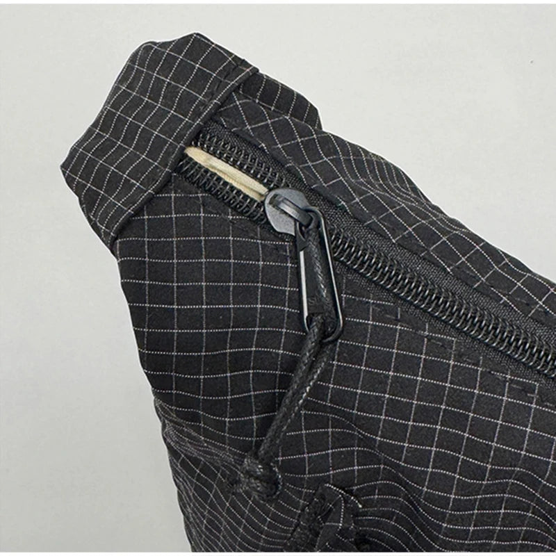 Close-up of a black plaid nylon drawstring tote bag featuring a zipper detail.