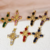 A collection of gold-plated cross and Virgin Mary charm pendants featuring various colored gemstones like pink, green, black,
