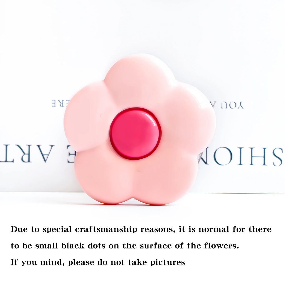 A pink flower shaped phone grip ring stand with small black dots on the surface.