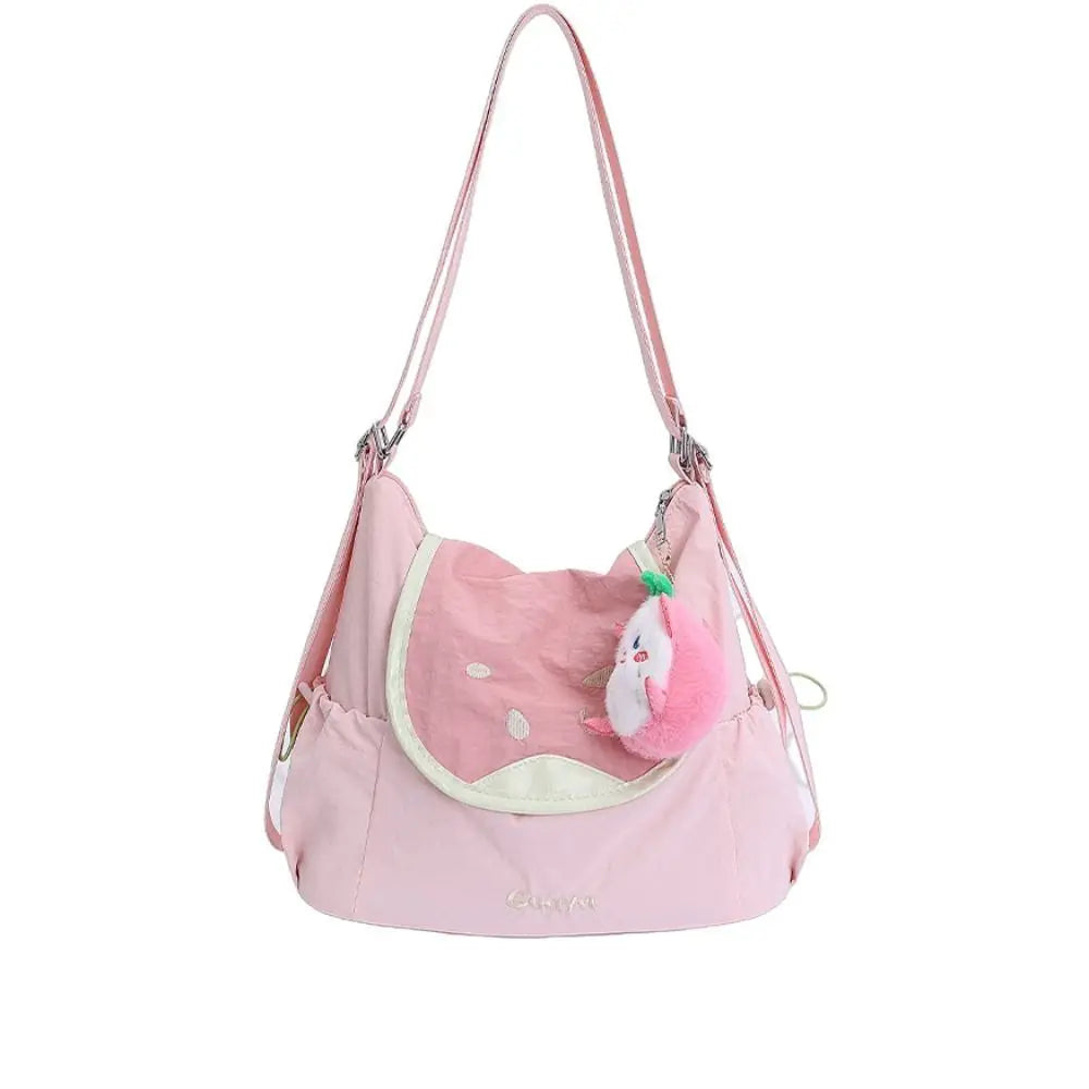 A pink nylon messenger backpack with a light pink fabric and a white fluffy pom-pom charm.