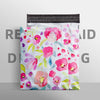 Une pile de sacs postaux blancs avec un motif floral rose et vert vibrant.