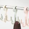 A close-up of a light colored multi-functional hanging hook with four claws hanging from a metal bar.