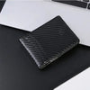 Black carbon fiber texture slim RFID-blocking credit card holder wallet placed on a dark surface.