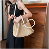 A woman wearing a black dress holds a straw woven tote bag with white PU trim and a matching pouch.