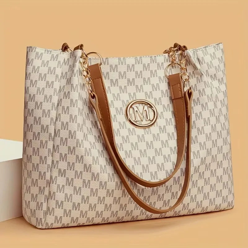 A beige geometric patterned tote bag with brown leather straps and gold hardware.