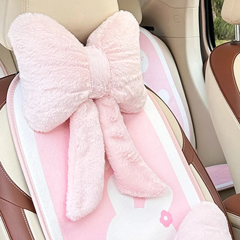 Pink faux fur bow knot car headrest pillow with lumbar support placed in a car seat.