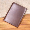 A brown genuine leather bifold card holder resting on a wooden surface.