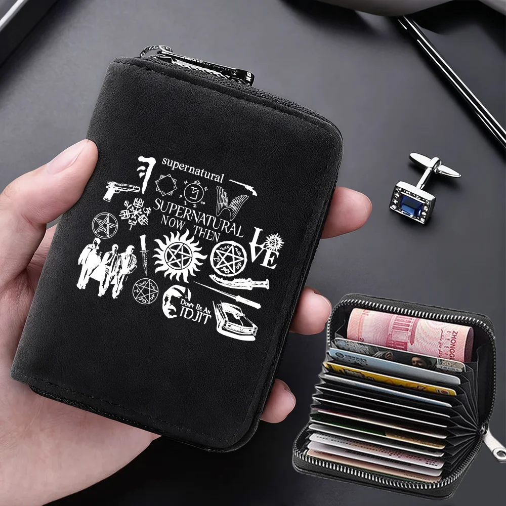 A black compact RFID-blocking card wallet with 11 slots is held in a hand, featuring supernatural and occult symbols.