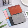 A stack of five PU leather card holder wallets in various shades of orange, teal, pink, and gray resting on a light surface.