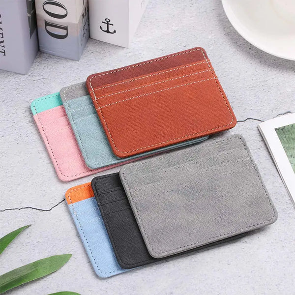 A stack of five PU leather card holder wallets in various shades of orange, teal, pink, and gray resting on a light surface.