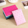 A stack of pink and teal heart print passport covers and a single pink heart print wallet on a wooden surface.