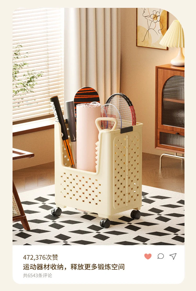 A cream-colored foldable laundry basket with mesh detailing is shown on a wooden floor next to a window.