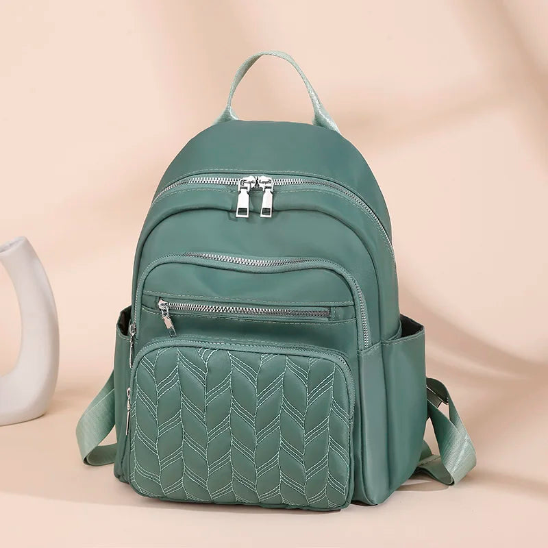 A teal waterproof women's travel backpack with quilted detailing shown against a light background.