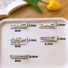 A white tray displaying various silver metal hairpins and clips of different sizes and shapes.