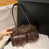 A brown leather vintage letter print crossbody bag is shown resting on a white surface.