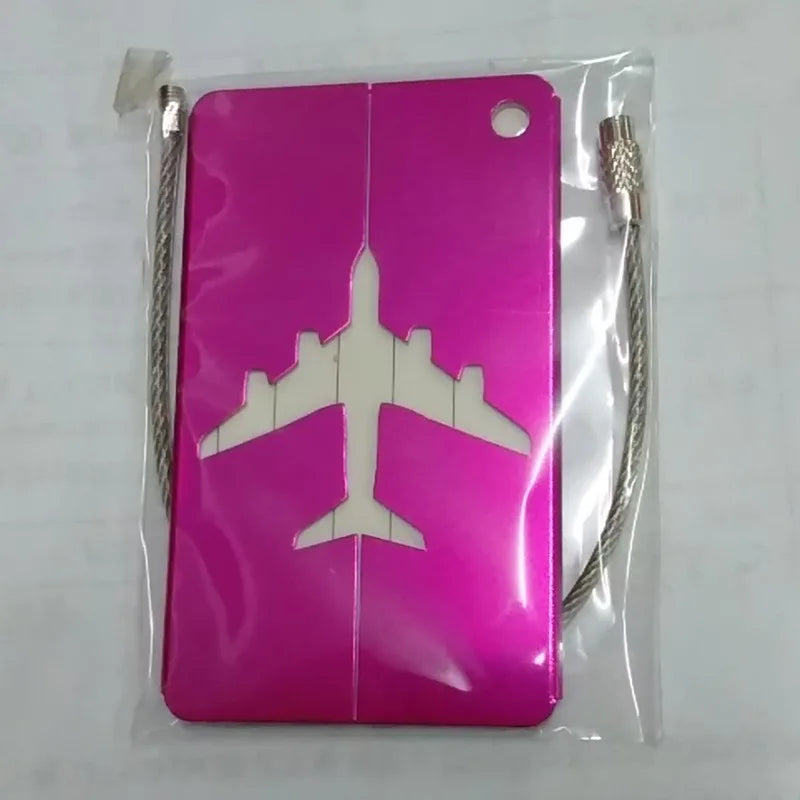 A pink durable aluminum luggage tag with a white airplane silhouette inside clear plastic packaging.
