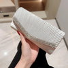 A hand holds a white luxury chain shoulder clutch bag with silver detailing.