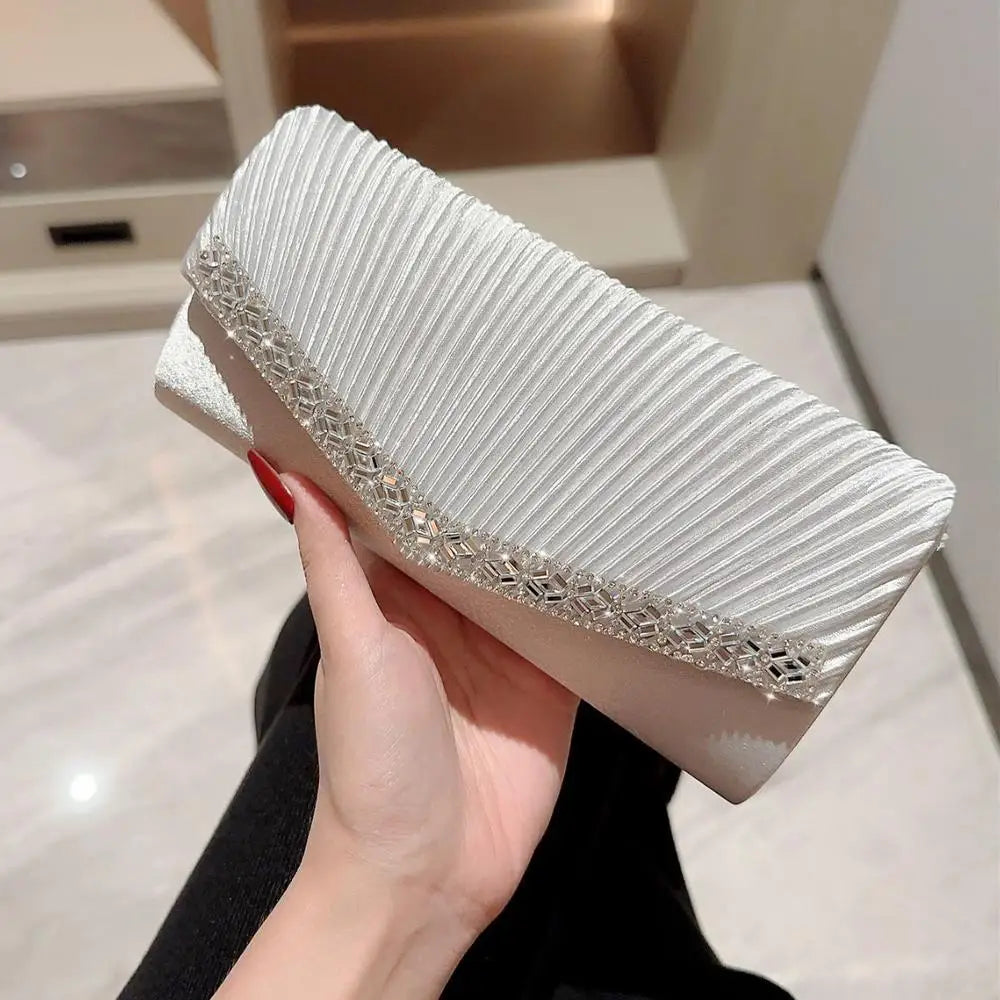 A hand holds a white luxury chain shoulder clutch bag with silver detailing.