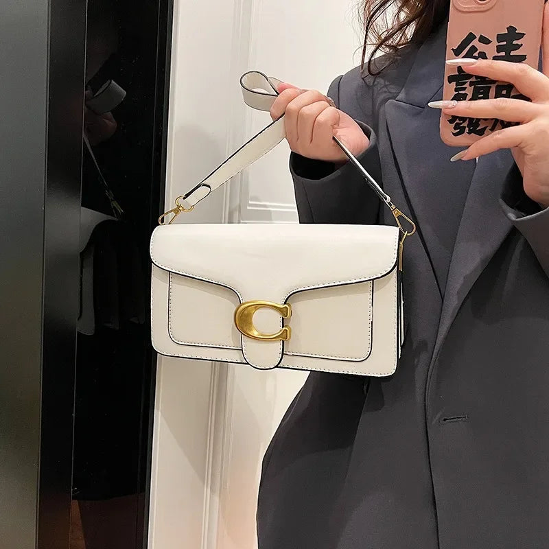 A woman holds a white leather shoulder bag with gold hardware against a light background.