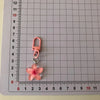 A pink resin flower keychain with a silver jump ring attached, measured against a ruler.
