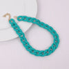 A turquoise acrylic chain necklace with a gold clasp laid on a white plate.